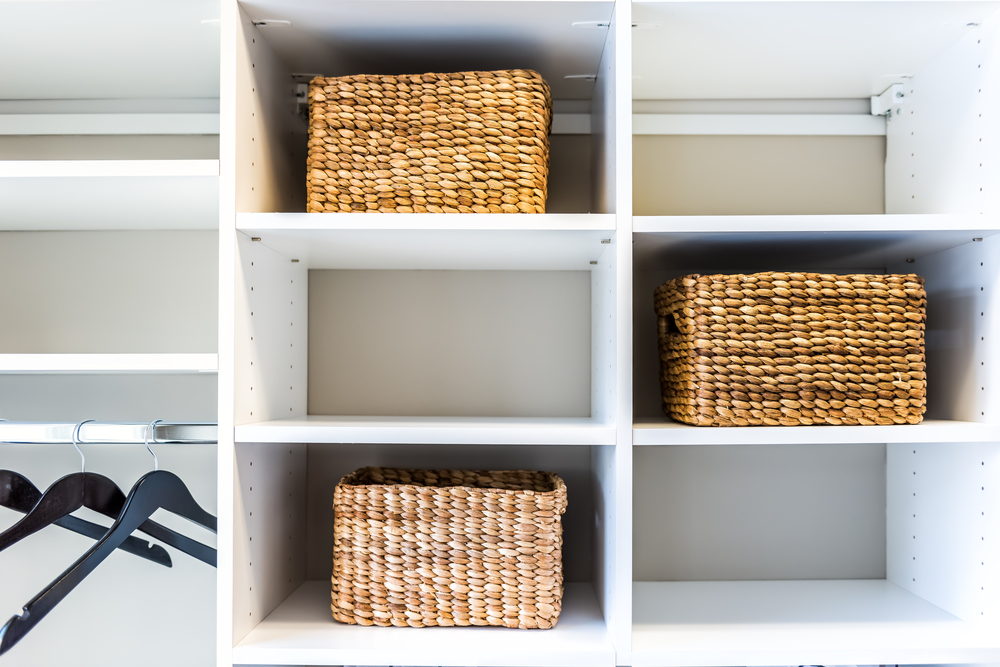 Cubbies with wicker baskets and hangers in storage closet