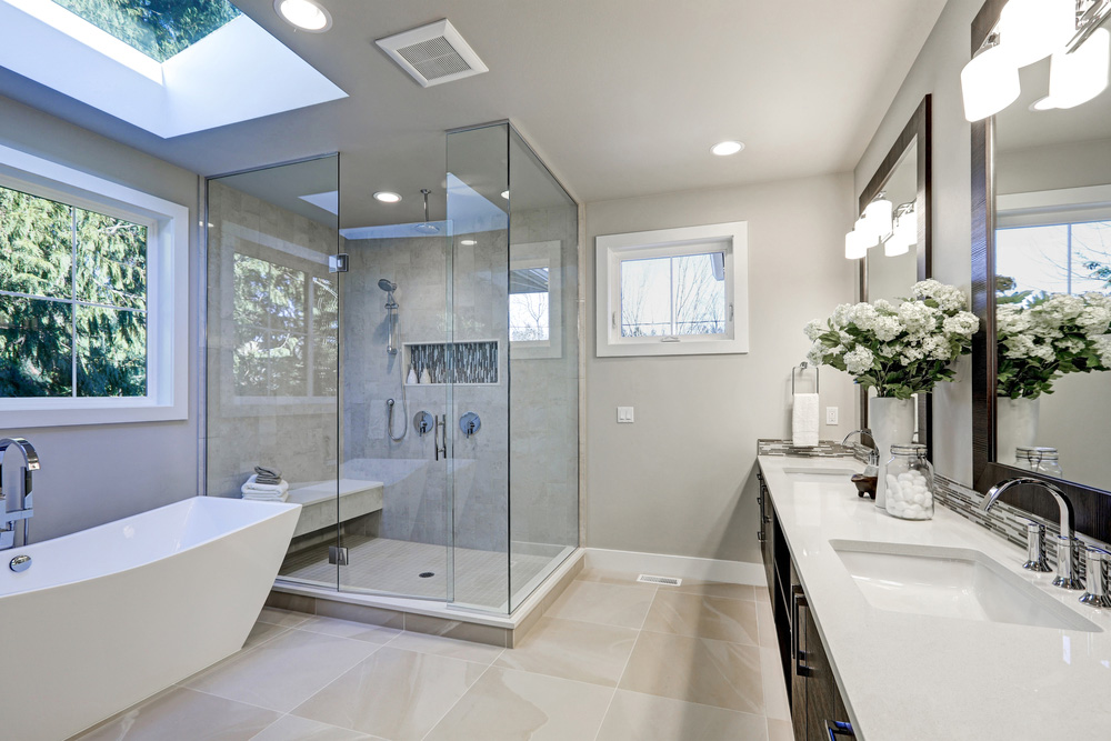 Renovated bathroom with glass-walled shower and stand-alone bathtub.
